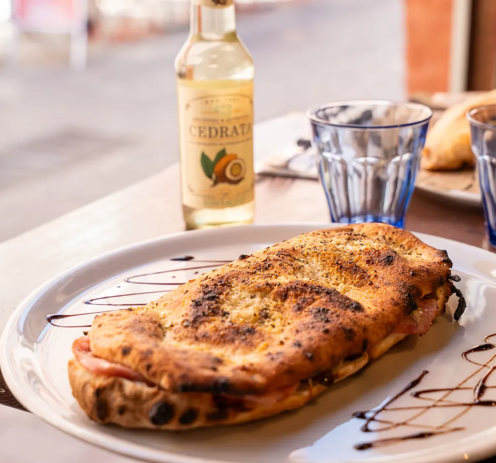 Un panuozzo doré sorti du four, sur une assiette en terrasse