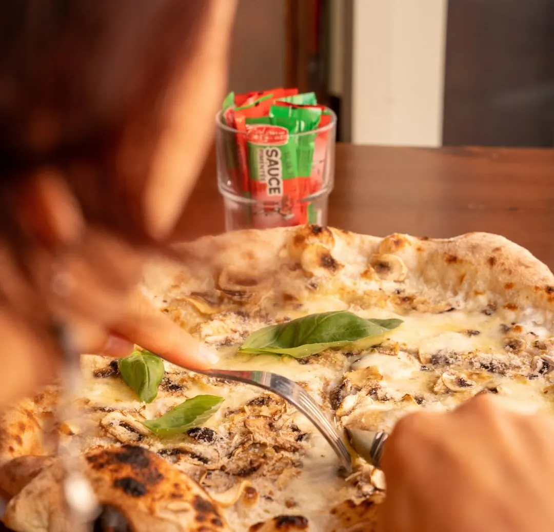 La pizza blanche aux champignons et basilic, coupée à la fourchette